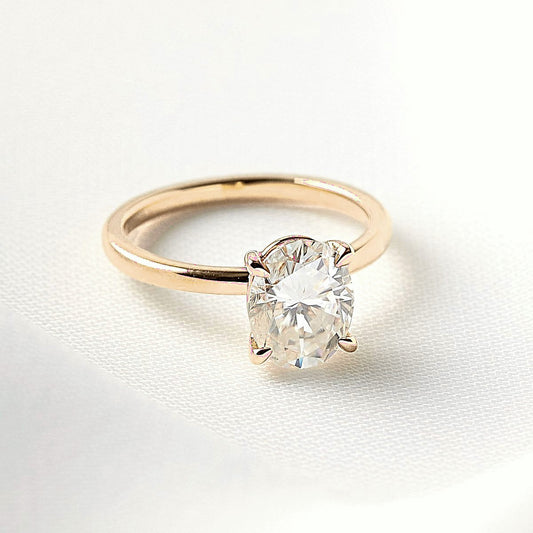 Aurora oval solitaire moissanite engagement ring in yellow gold on white silk
