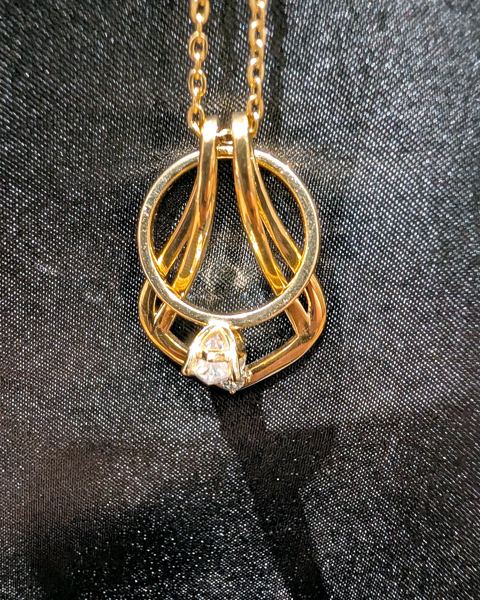 Gold ring holder necklace cradling a solitaire engagement ring
